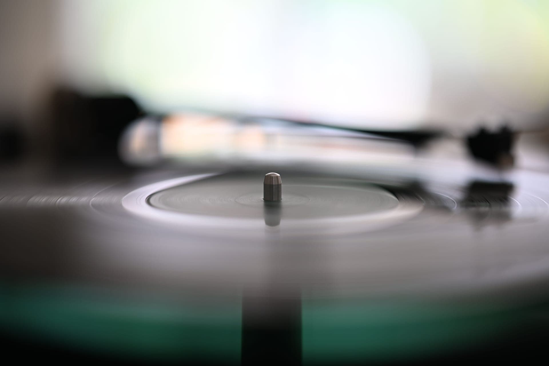 A hi-fi turntable with the platter spinning and the tonearm tracking a record, lit in warm low light