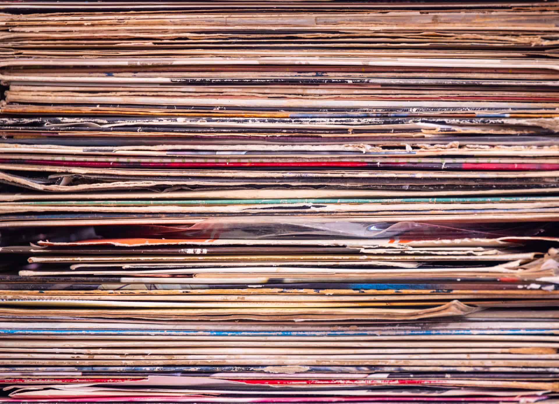 A stack of vinyl records beside their sleeves in warm light