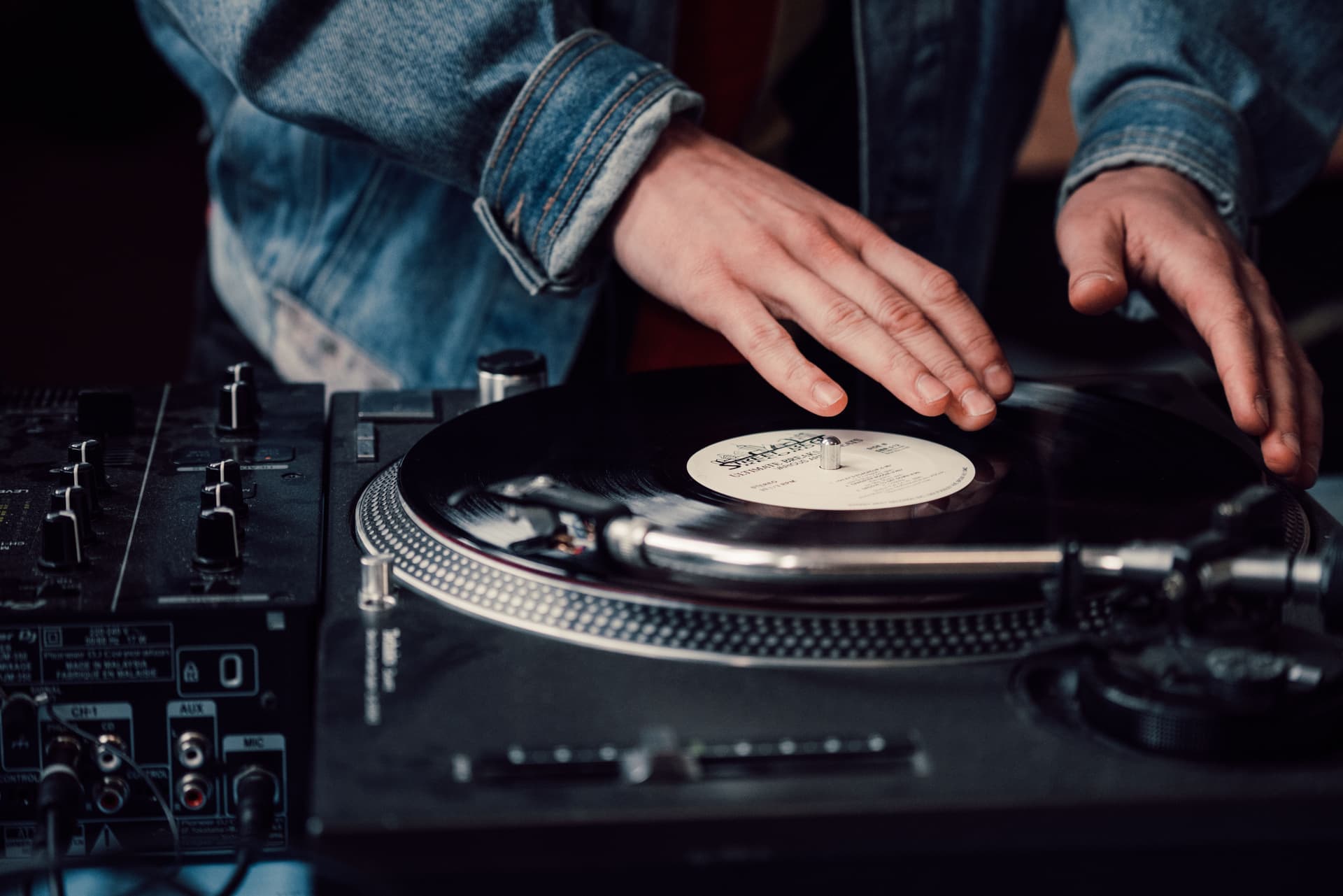 Hands adjusting a turntable tonearm during setup