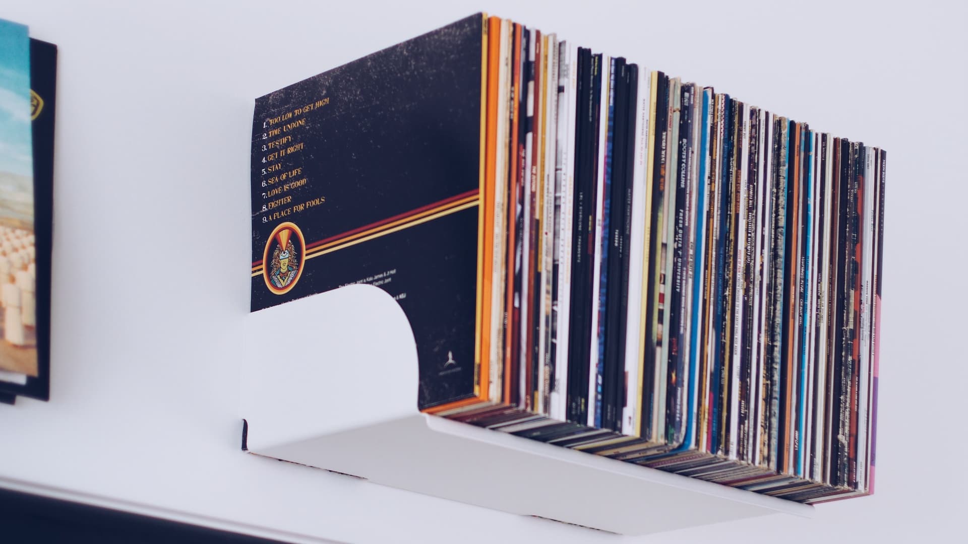 Vinyl records stored upright on a shelf in warm light