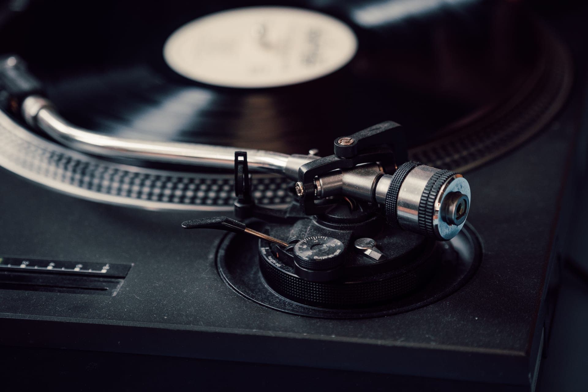 A turntable platter and tonearm lit in warm low light